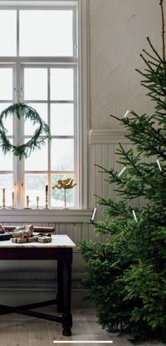 a christmas tree in front of a window with wreaths and candles on the windowsill