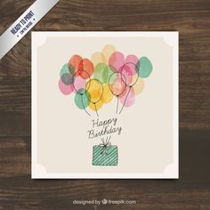 a birthday card with balloons and a present on the front, sitting on a wooden surface