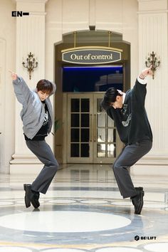 two young men jumping in the air with their arms spread out and one man wearing a suit