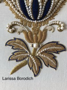 an embroidered piece with pearls and leaves on it