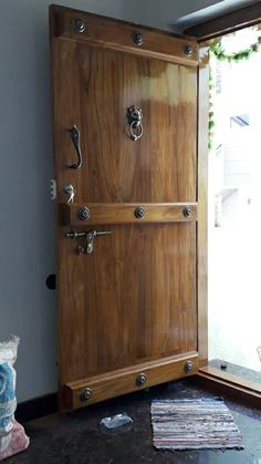 an open wooden door with metal handles on the front and side, next to a pile of papers