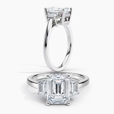 a three stone engagement ring with an emerald cut diamond in the center and side stones