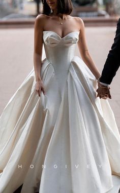 a woman in a white wedding dress holding the hand of a man