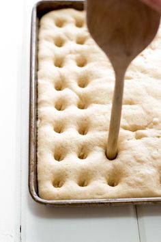 a wooden spatula is being used to mix batter into the dough in a pan