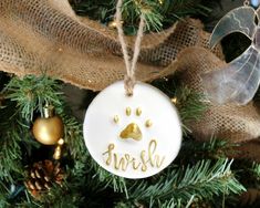 a christmas ornament hanging from a tree with ornaments around it and the word's name on it