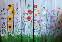 a painting of flowers painted on wood planks with green grass and blue sky in the background