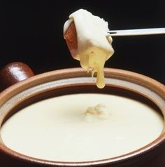 a person dipping some food into a bowl with a toothpick in the middle