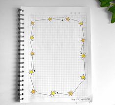 a notebook with yellow stars on it next to a green plant and pencil sharpener