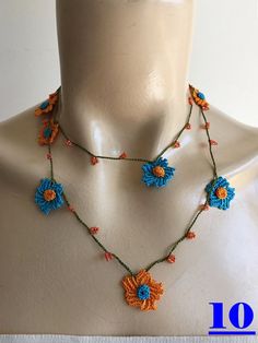 a white mannequin with a blue and orange flower necklace on it's neck