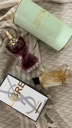 two bottles of perfume sitting on top of a bed