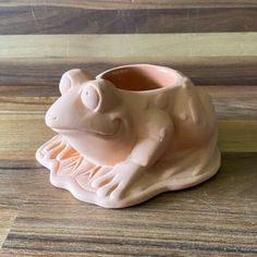 a ceramic frog vase sitting on top of a wooden table