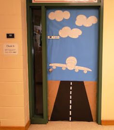 a door decorated with an airplane on the road and clouds in the sky above it