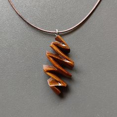 a necklace with three wooden pieces hanging from it's side on a gray surface