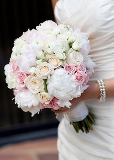 a bride holding a bouquet of white and pink flowers