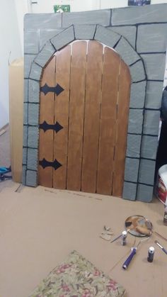 a wooden door with arrows painted on it in front of a brick wall and floor