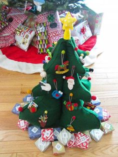 a small christmas tree made out of cloths on the floor next to a pile of presents