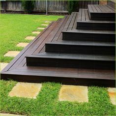 the steps are made out of wood and have grass growing on each side, along with stepping stones