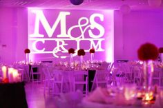 the reception room is set up with white chairs and purple lighting, along with tall centerpieces that spell out mr and mrs