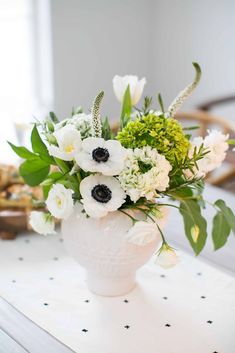 a white vase filled with flowers on top of a table