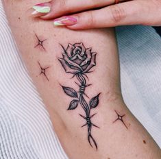 a woman's arm with a rose tattoo on it and stars in the background