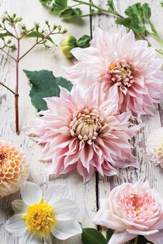 pink and white flowers are arranged on a wooden surface