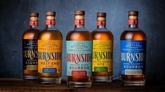 three bottles of bourbon sitting on top of a wooden table