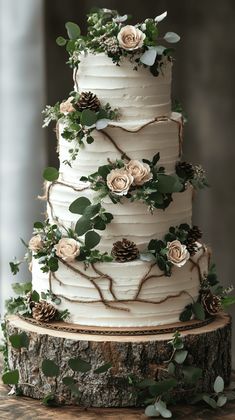 a wedding cake with white frosting and greenery on the top is sitting on a tree stump