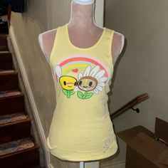 Tokidoki Rare Vintage Tank Top, Ribbed Style, Sizes Small, Large And Xl Available, Pale Yellow Color, Front Features Large Graphic Print Of Flower Characters And Rainbow, Bottom Features Tkdk Heart And Crossbones Logo In Rhinestones, Back Features Small Graphic Print Of Flower Character And Tkdk Logo, Brand New With Tags, Very Rare And Hard To Find, Purchased From Australia! Playful Fitted Tank Top For Spring, Playful Cotton Tank Top For Spring, Fun Cotton Tank Top For Spring, Fitted Fun Tank Top For Spring, Cute Spring Cotton Tank Top, Playful Sleeveless Top With Character Print, Playful Multicolor Cotton Tank Top, Playful Cotton Tank Top, Casual Cotton Tank Top With Character Print