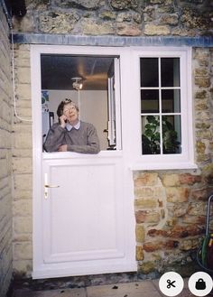 a man talking on a cell phone while standing in front of a white door with two windows