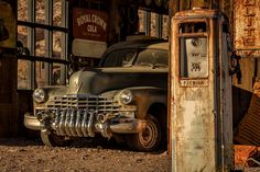 an old car is parked in front of a gas pump