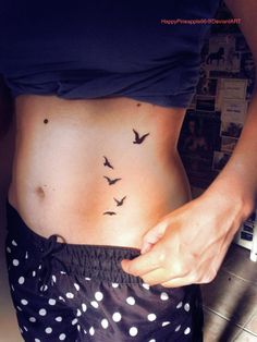 a woman's stomach with birds on it and polka dot shorts underneath her belly