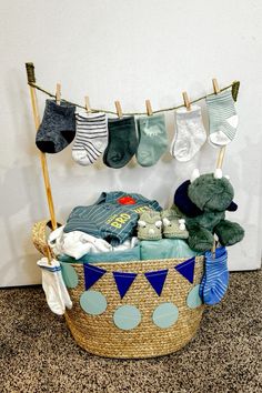 a basket filled with baby items and socks hanging from clothes pins on a clothes line