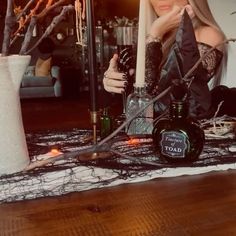 a woman sitting on the floor with candles and bottles in front of her, surrounded by branches