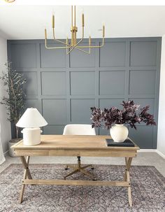 a living room with grey walls and a wooden table topped with two white vases