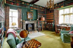 a living room filled with lots of green furniture and bookshelves full of books