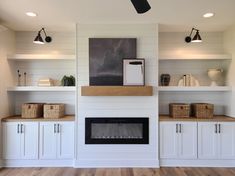 a living room with white walls and wooden flooring, built in shelving units