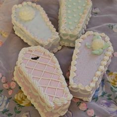 four decorated cookies sitting on top of a purple cloth covered table with pink and white frosting