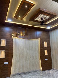 an empty room with wood paneling and lights on the ceiling is lit by recessed lighting