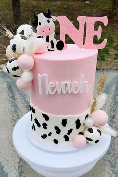 a pink and black cake with cow decorations on top