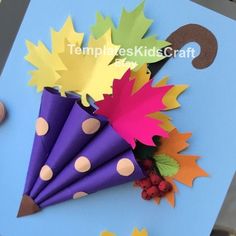 an umbrella made out of paper with leaves and berries on the table next to it