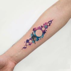 a person's arm with a colorful watercolor tattoo design on the left forearm