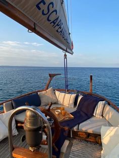 an outdoor seating area on the deck of a sailboat in the open ocean with blue sky and white clouds