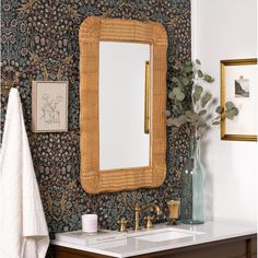 a bathroom sink with a mirror above it next to a towel rack and wall paper