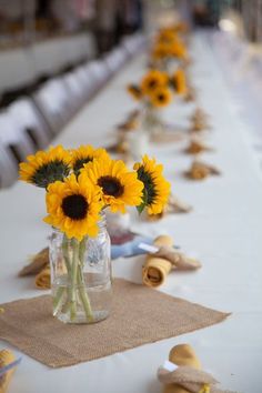 sunflowers are arranged in vases on a long table