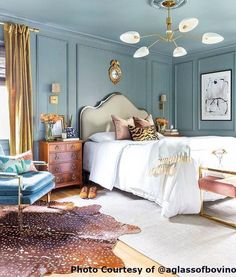 a bedroom with blue walls and white bedding, rugs on wooden flooring