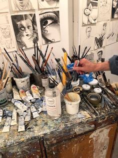 a man is painting on an easel with lots of paintbrushes and brushes