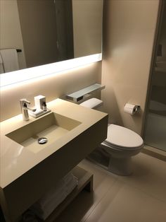 a white toilet sitting next to a sink in a bathroom under a large mirror above it