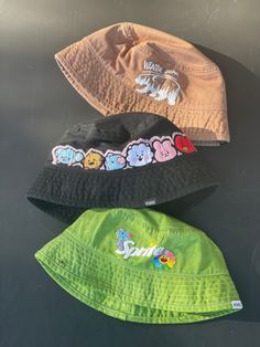 BTS hand embroidered and hand dyed bucket hats, perfect to rep your bias or your love for OT7! These are cotton bucket hats in a one size fits most sizing -Winter bear Taehyung V design on a light brown hat -BT21 baby design on a black bucket hat  -J-hope sprite design with hope world flower on a green bucket hat  Order your Hobi hat in time for lollapalooza! Playful Cotton Bucket Hat With Short Brim, Playful Cotton Bucket Hat, One Size, Trendy Summer Bucket Hat With Embroidered Logo, Fun Cotton Hats For Streetwear, Trendy Bucket Hat With Embroidered Logo, Fun Short Brim Cotton Hats, Handmade Green Cotton Bucket Hat, Cute Streetwear Hats, Cute Handmade Cotton Hat