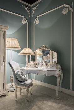 a white desk with a chair and two lamps on top of it next to a mirror