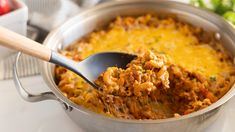 a spoon full of macaroni and cheese being lifted from a pot